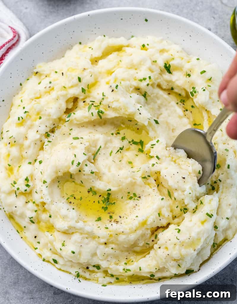 Stirring fluffy vegan mashed potatoes with a large spoon in a pot.