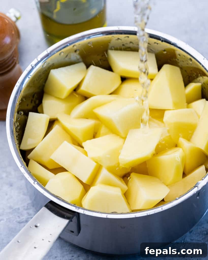 Pouring water into a pot filled with chopped potatoes before boiling.