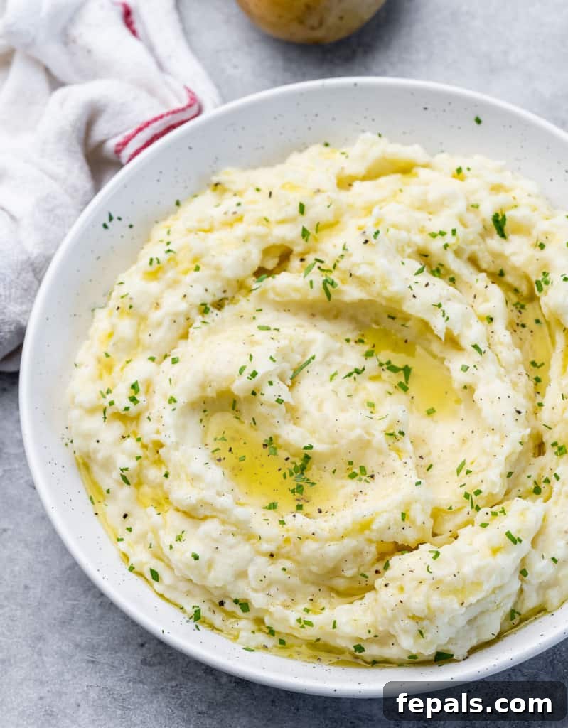 top view mash potato on a white plate with melted vegan butter and fresh herbs