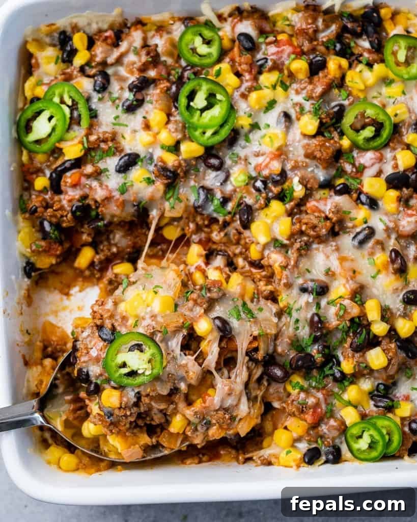 A serving of a warm Mexican casserole being cut from the dish, showing layers of ingredients.