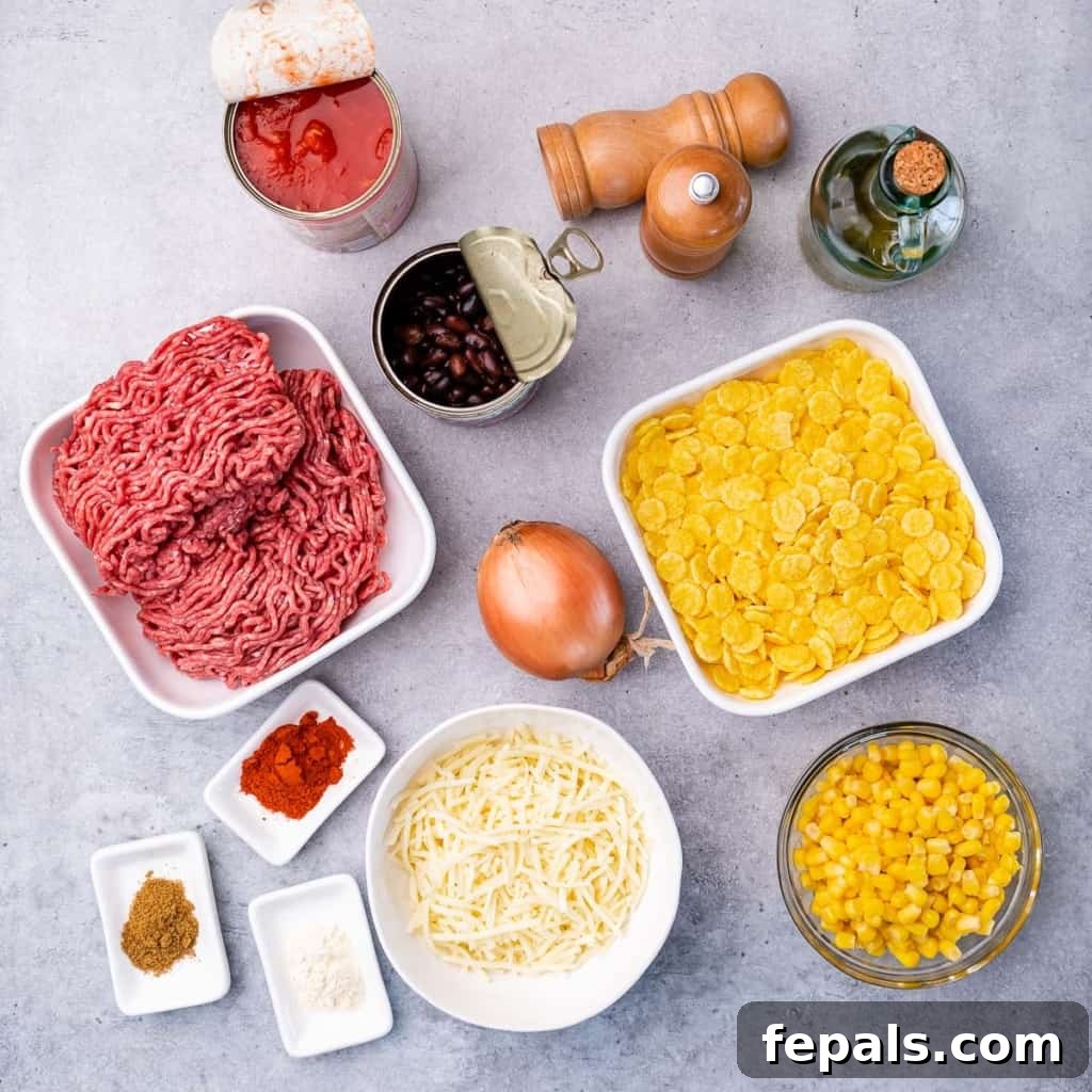 Arrangement of taco casserole ingredients in small bowls: olive oil, ground beef, onion, spices, beans, corn, tomatoes, cheese, and chips.