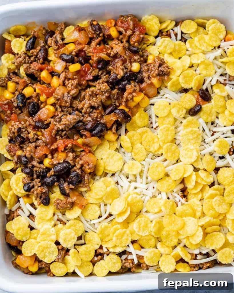 Layering process of taco casserole with crushed cornflakes, beef mixture, and cheese in a baking dish.