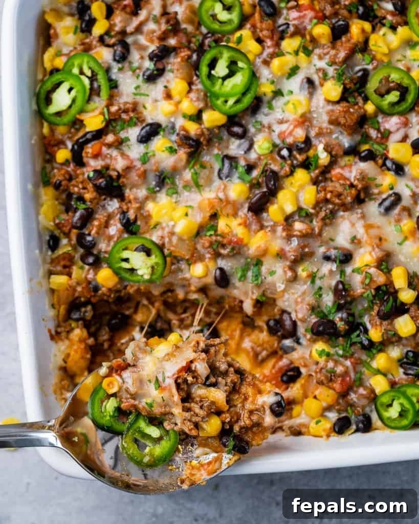 A serving of taco bake being scooped from the dish, revealing rich layers.