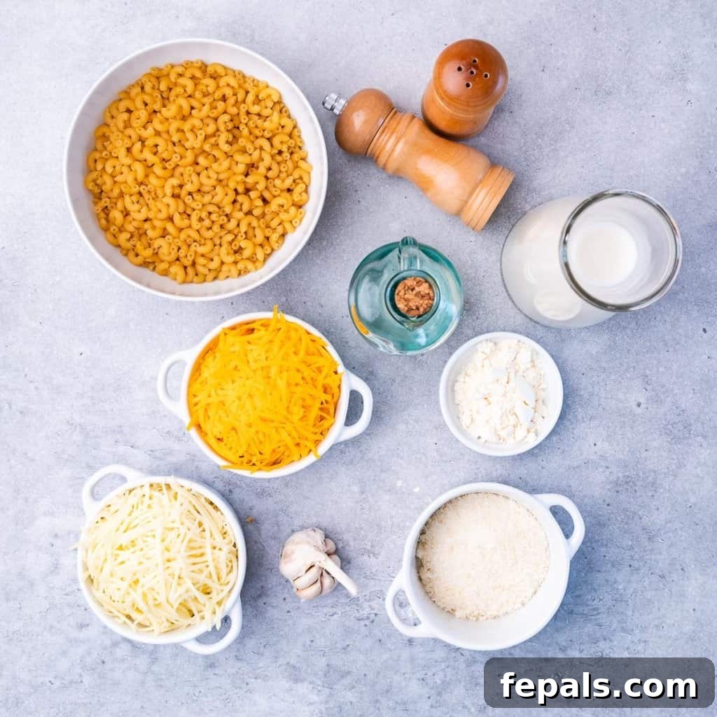 Close-up of divided ingredients: macaroni, garlic, milk, cornstarch, shredded cheddar, Gruyere, and Parmesan cheese.