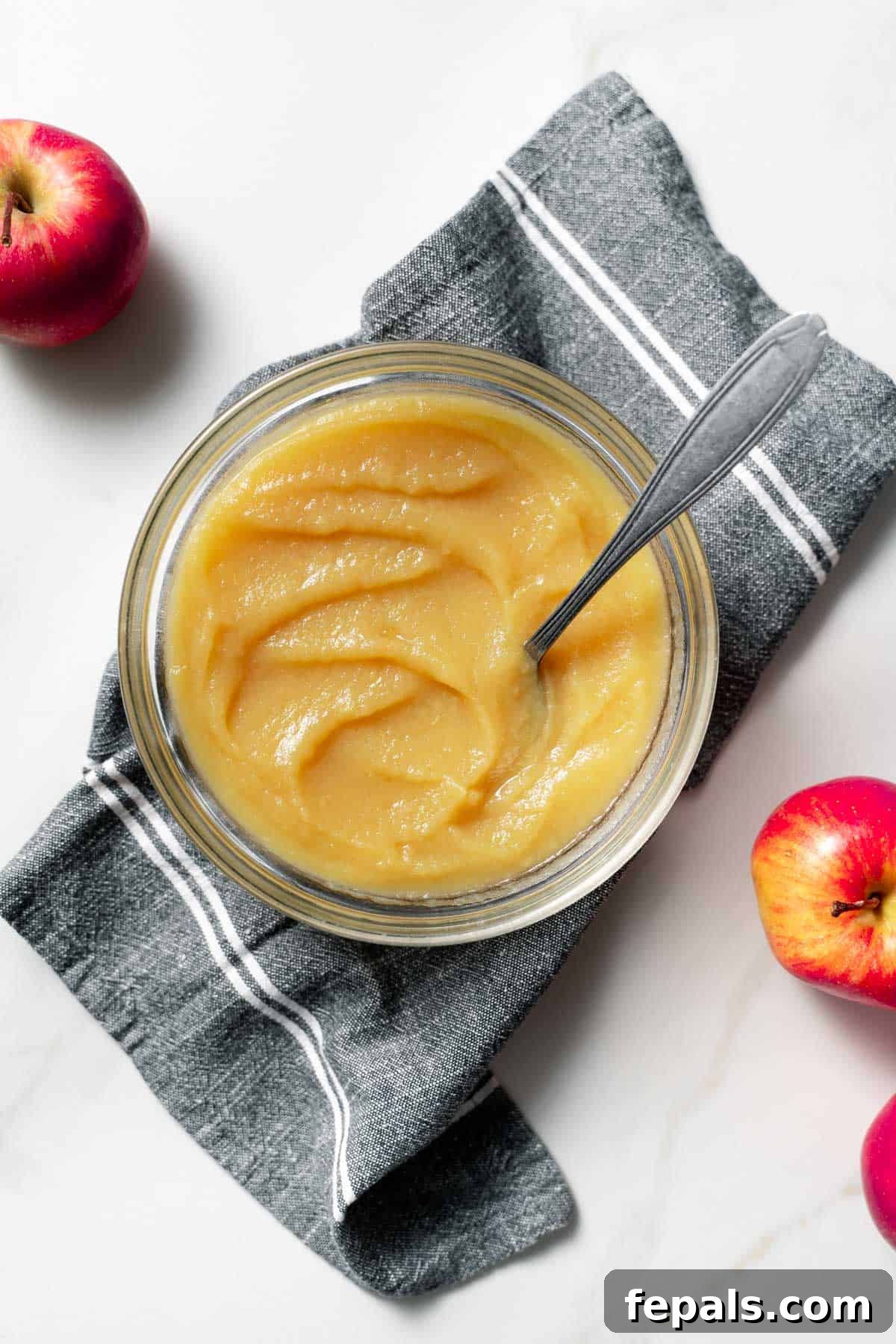 top view of jar filled with apple sauce and spoon 