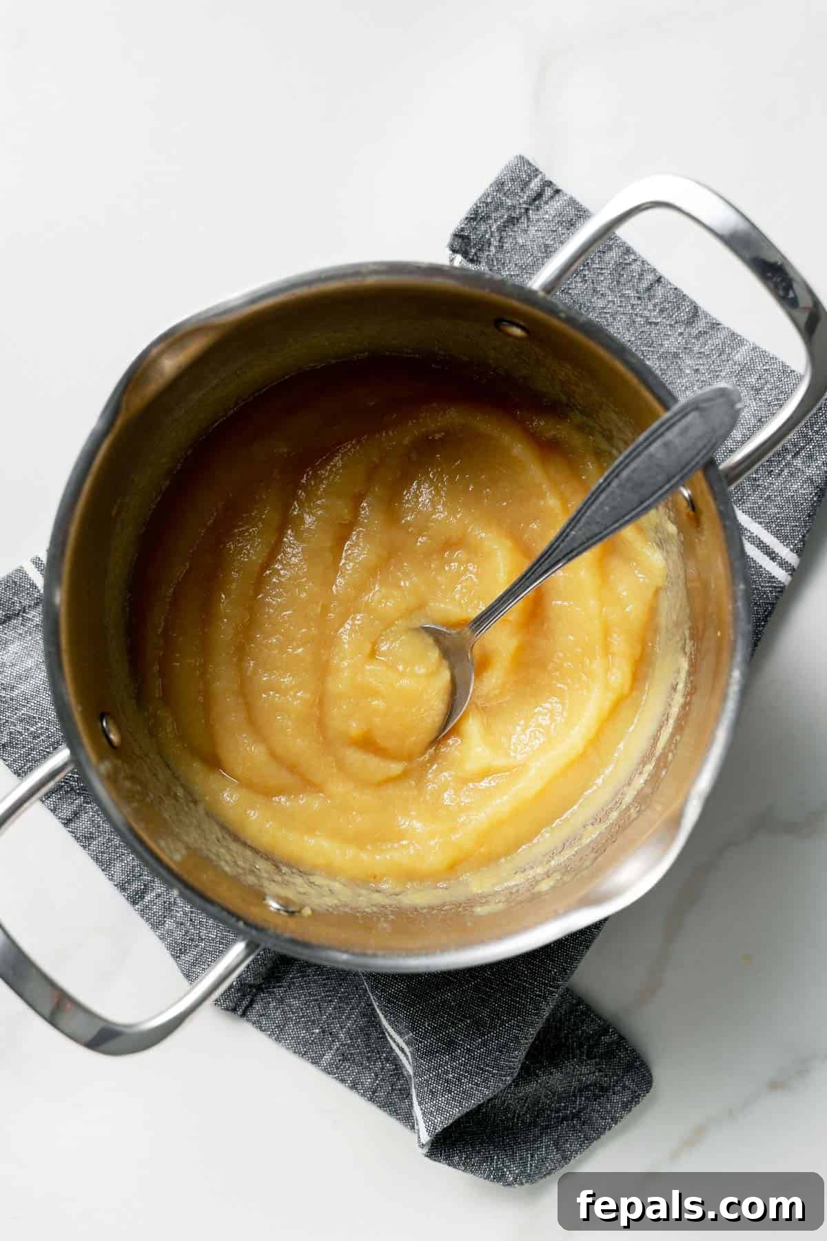 pureed apples in pot with spoon 