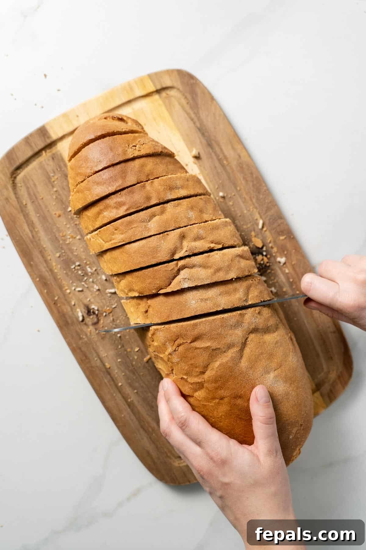 How To Make Croutons slicing one loaf of bread with knife atop cutting board