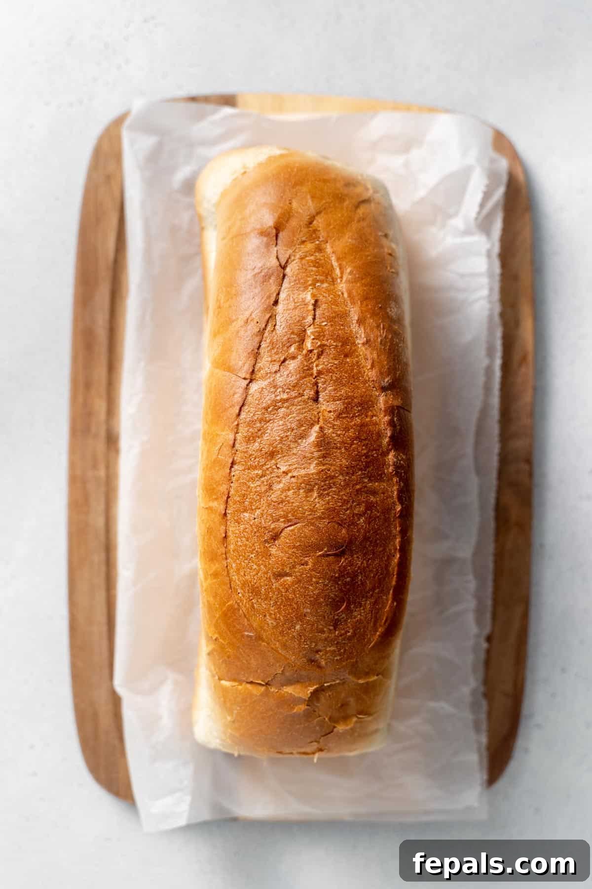 How To Make Breadcrumbs one loaf of bread atop parchment paper and cutting board