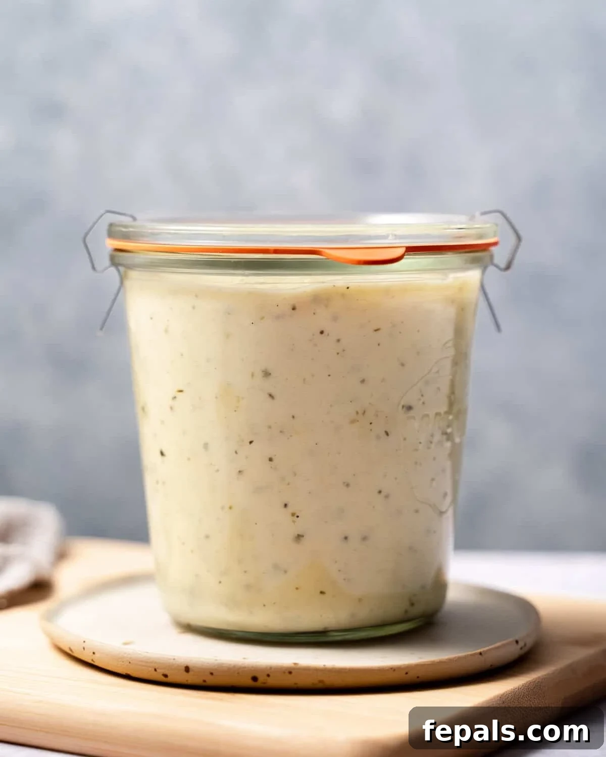 Healthy Alfredo Sauce stored in a transparent glass jar, ready for future use.