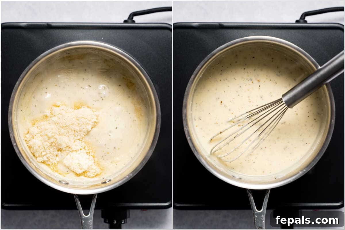 Grated Parmesan cheese being poured over the thickened Alfredo sauce in a saucepan, ready to be whisked until smooth.