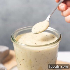 side shot of homemade alfredo sauce in a jar, showcasing its rich and creamy texture.