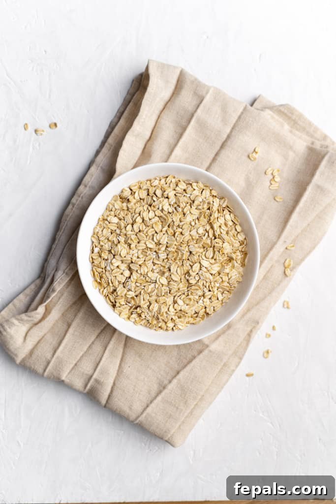 A white bowl filled with rolled oats, sitting on a natural linen napkin, ready for processing into flour.