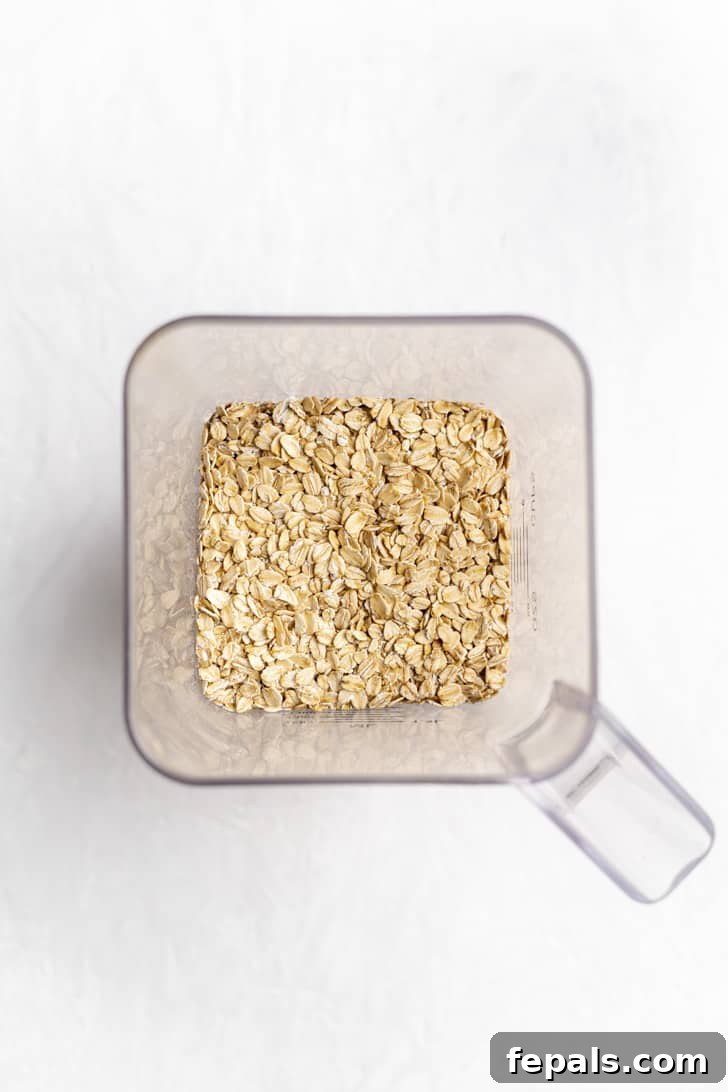 Rolled oats being poured into the blending container of a high-speed blender.