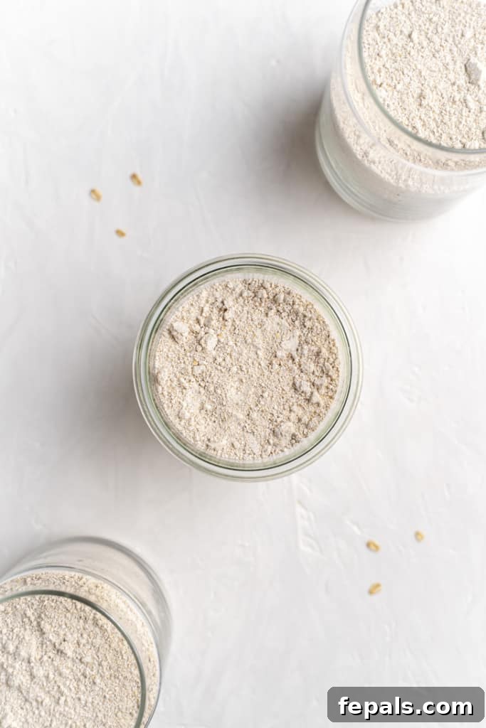 A close-up top view of golden oat flour neatly settled in a glass jar with its lid off, ready for culinary use.