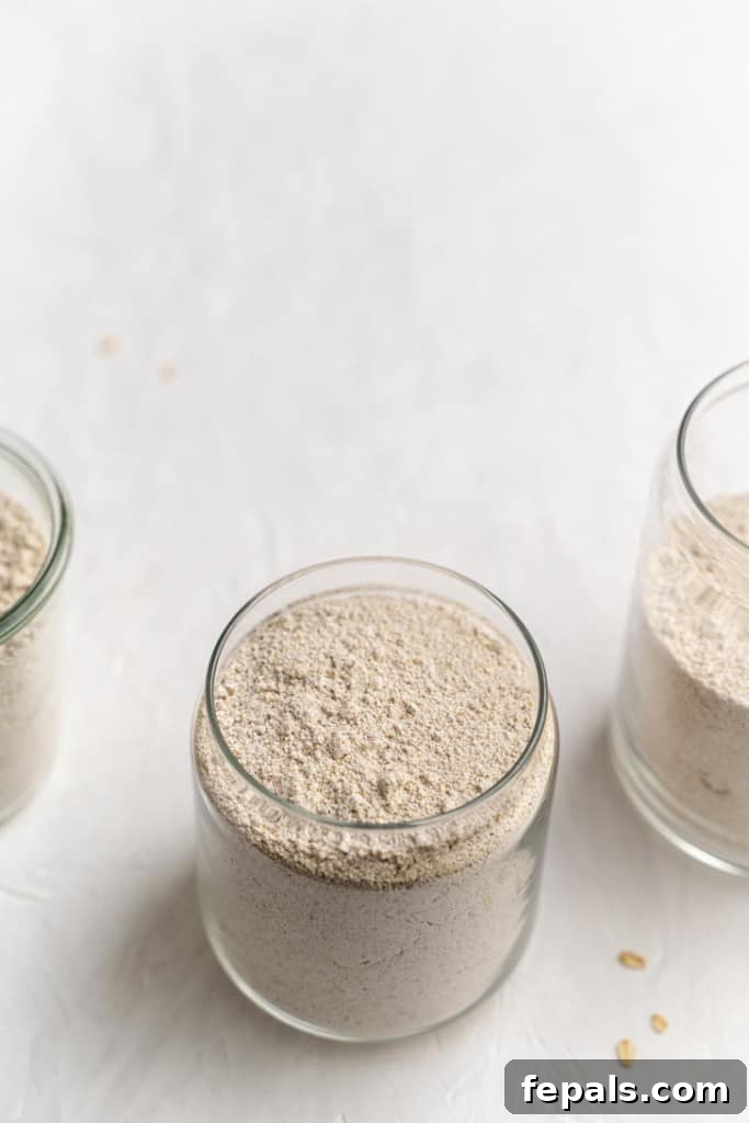 Two glass jars filled with homemade oat flour, their lids removed, ready for storage or immediate use in baking.