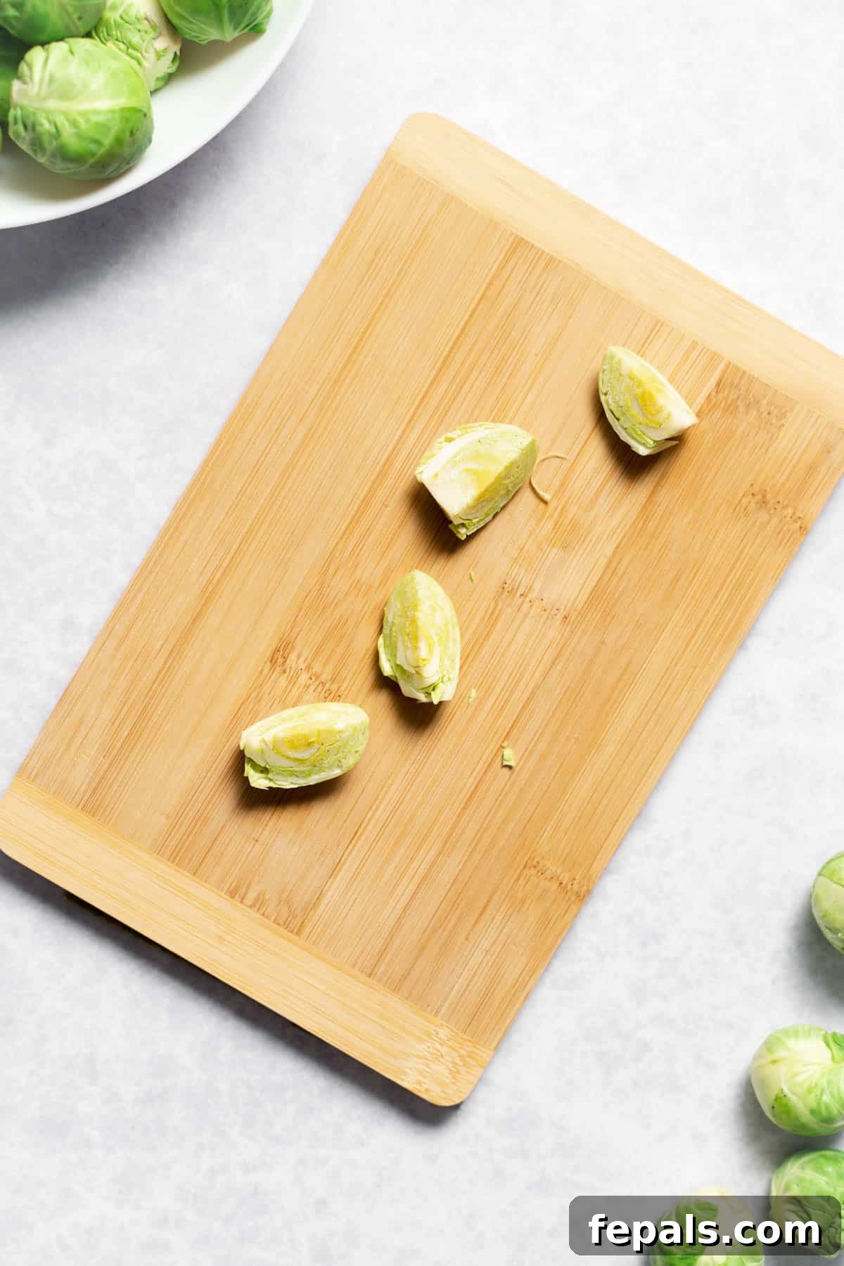 How To Cut Brussels Sprouts Four evenly cut quartered Brussels sprouts on a wooden cutting board
