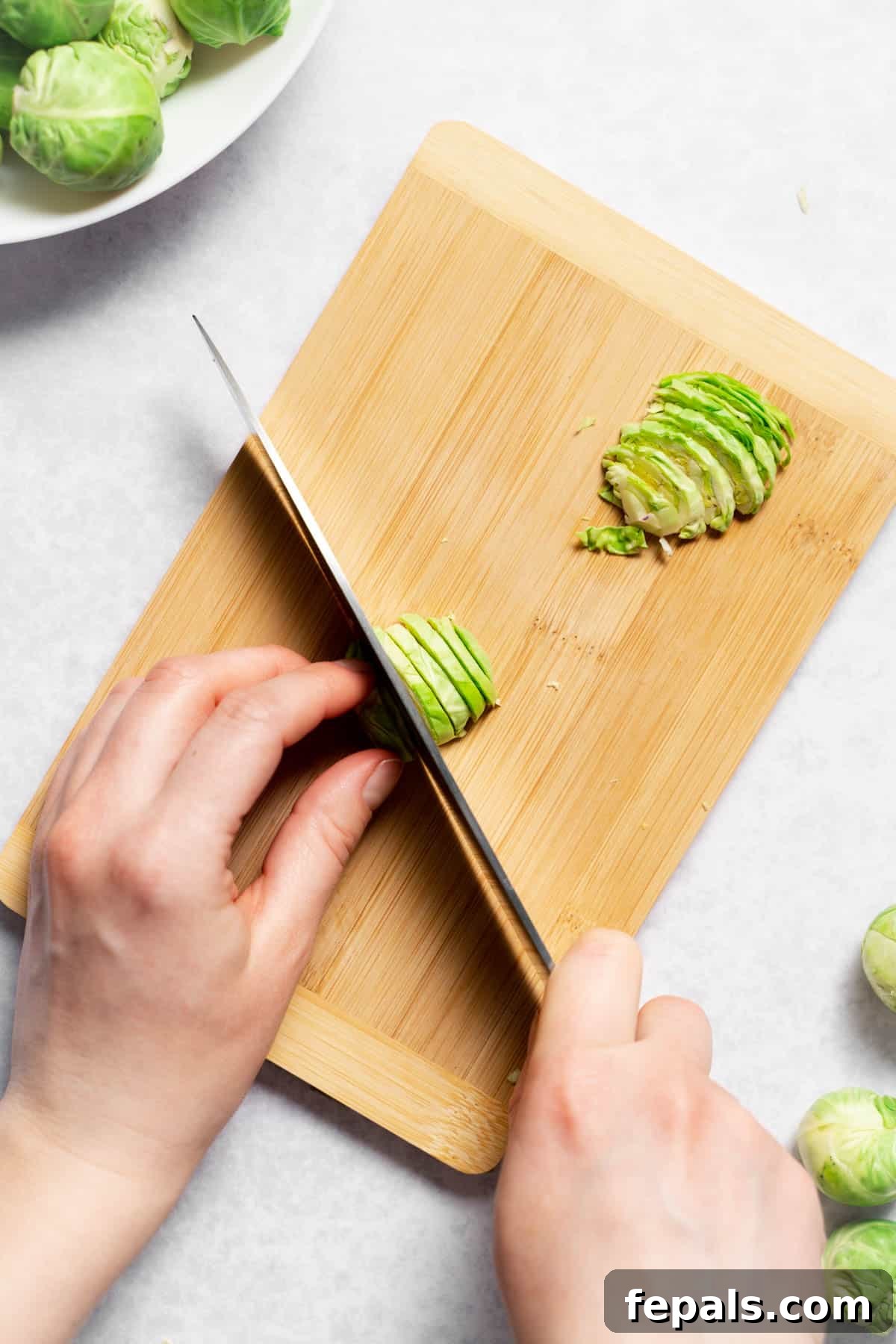 How To Cut Brussels Sprouts Finely chopping sliced Brussels sprouts with a rocking knife motion