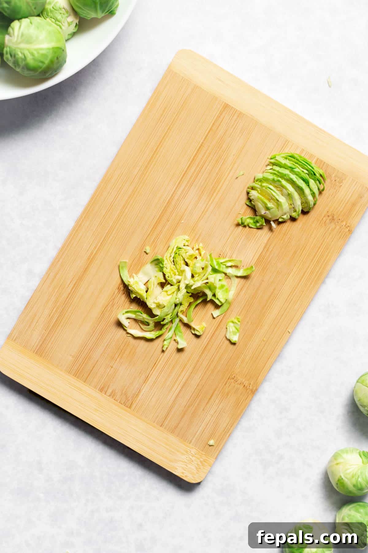 How To Cut Brussels Sprouts Heap of finely chopped Brussels sprouts on a wooden cutting board, ideal for salads