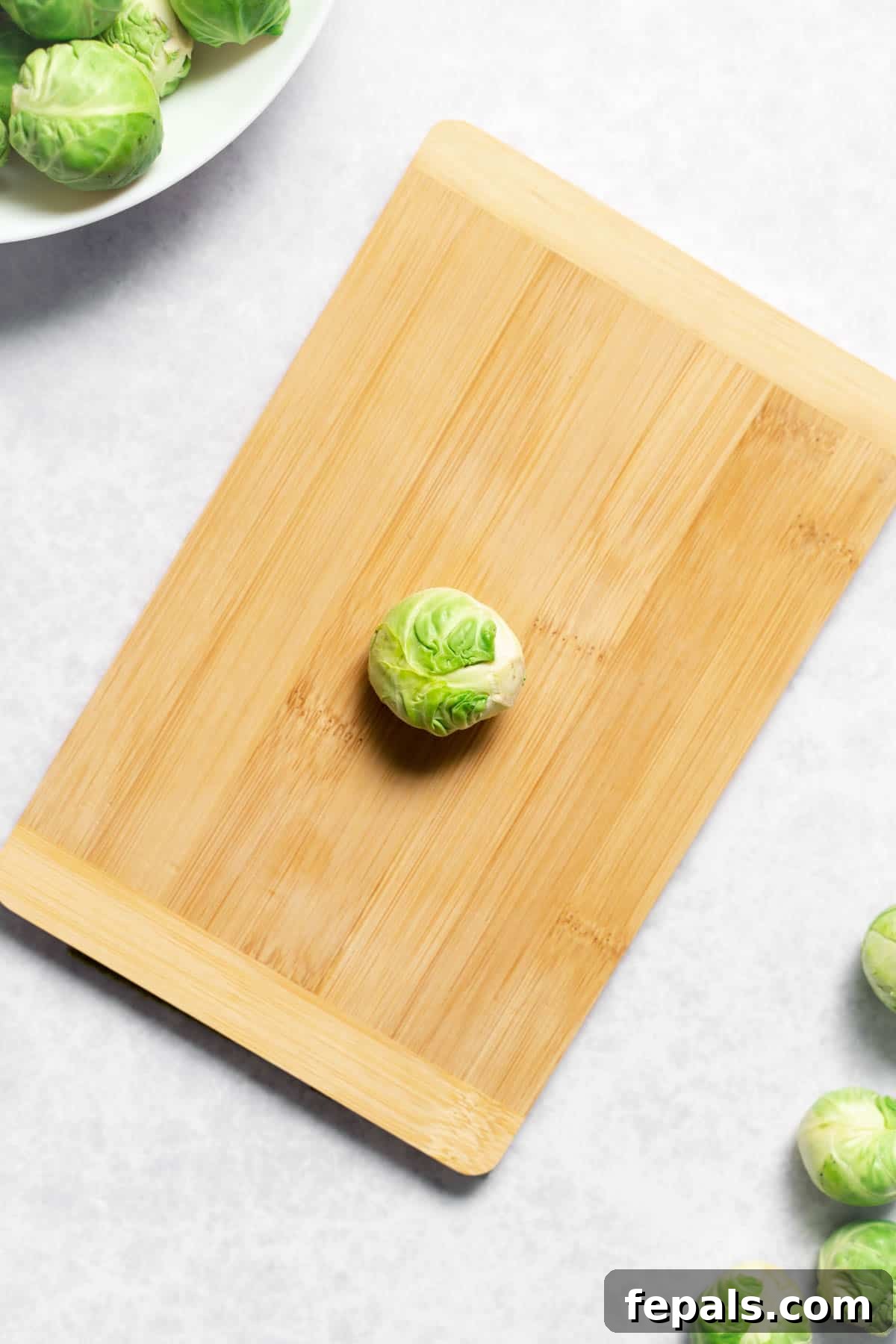 How To Cut Brussels Sprouts Single Brussels sprout atop a wooden cutting board, ready for preparation