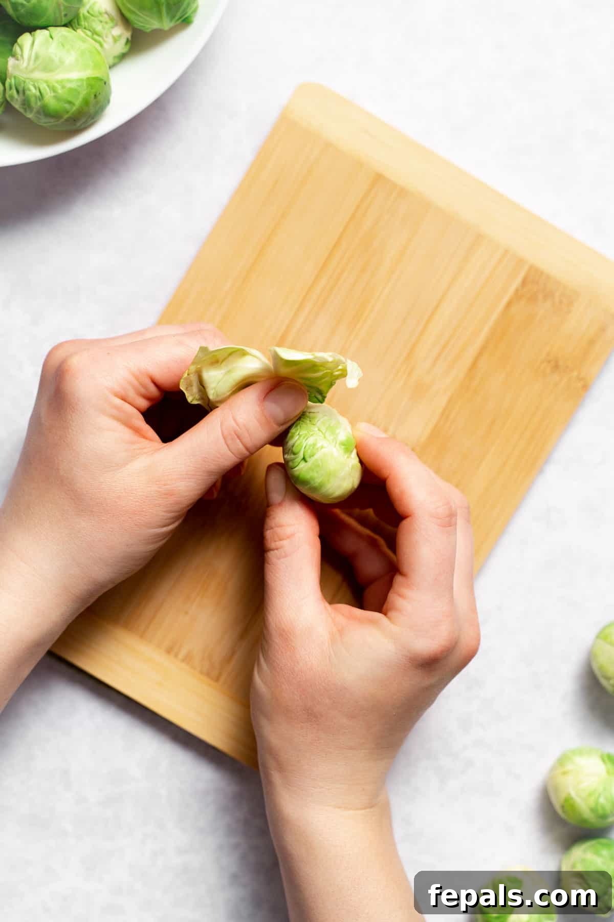 How To Cut Brussels Sprouts Hand peeling loose outer leaves from a Brussels sprout