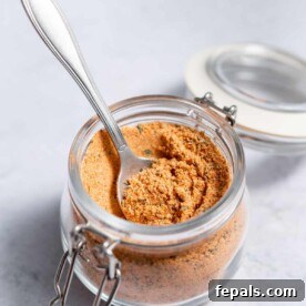 side shot of cajun seasoning in a jar with spoon in it