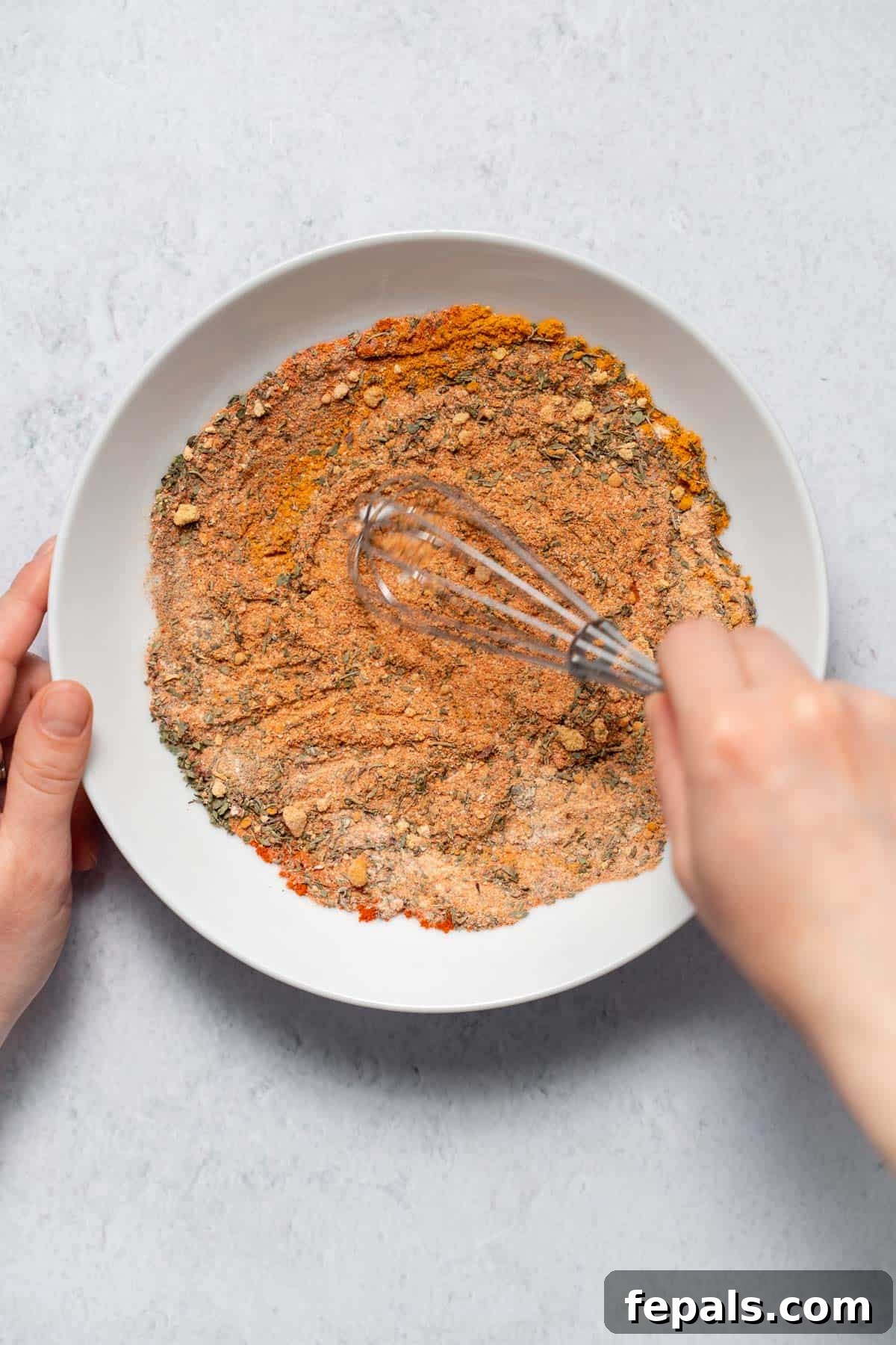 mixing spices and herbs in bowl with whisk