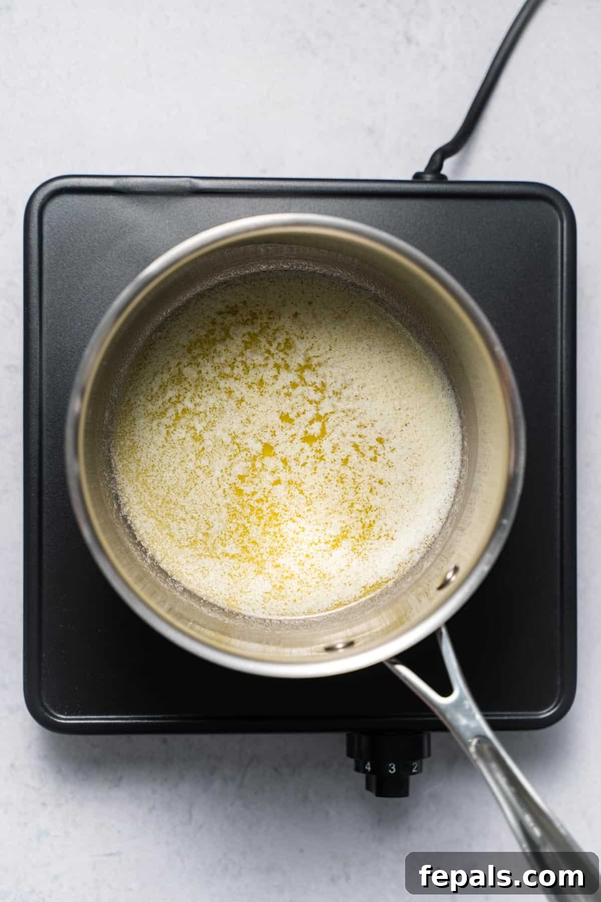 A small saucepan filled with completely melted, golden butter, shimmering on the stovetop.