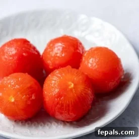 image of 5 peeled tomatoes on a white plate