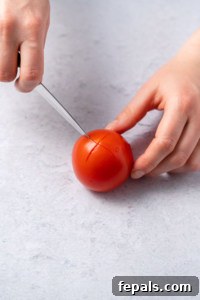 cutting an X in bottom of tomato with knife