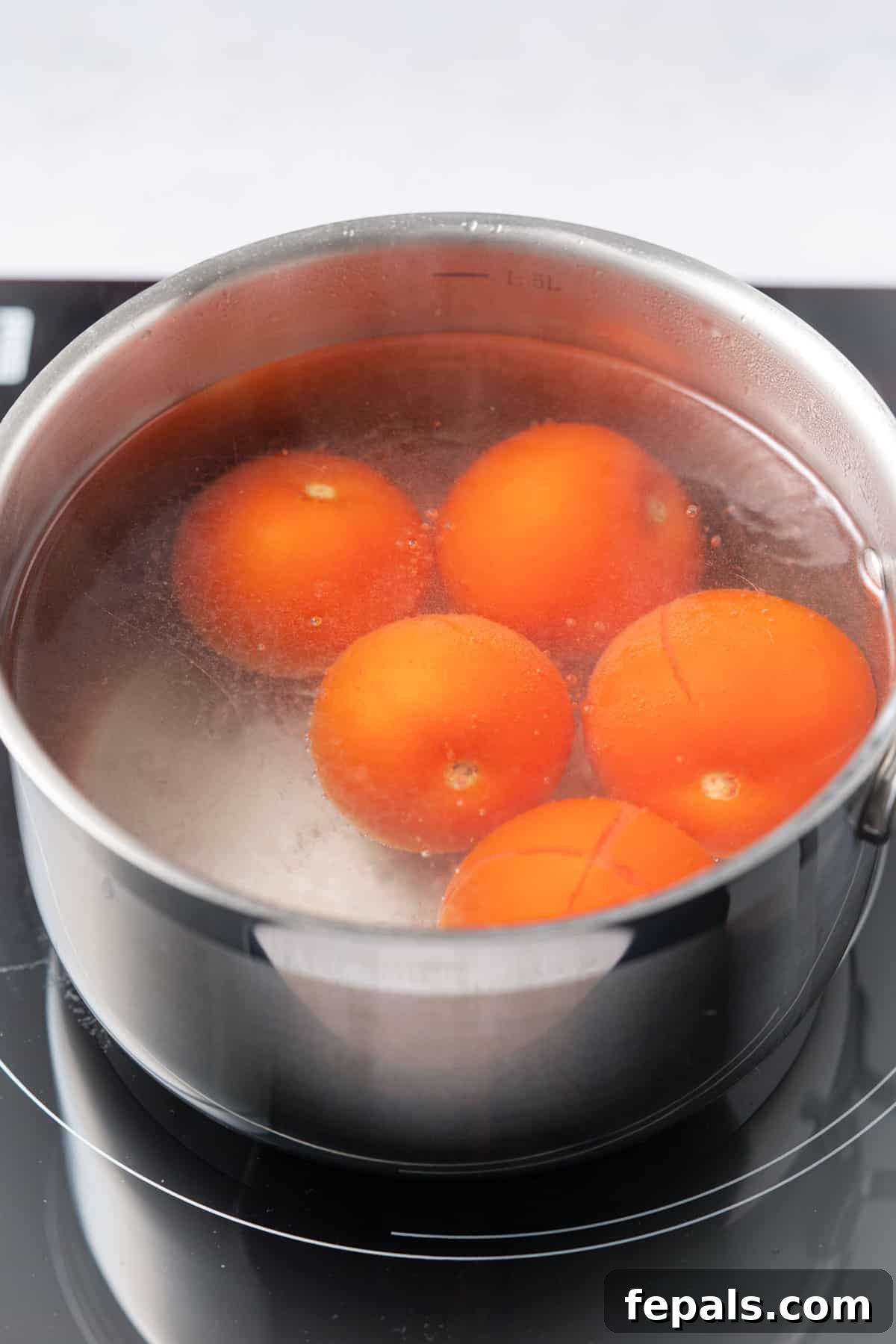 The Simple Trick to Perfectly Peeled Tomatoes 5 Several ripe tomatoes submerged in a pot of vigorously boiling water, indicating the blanching process in action.