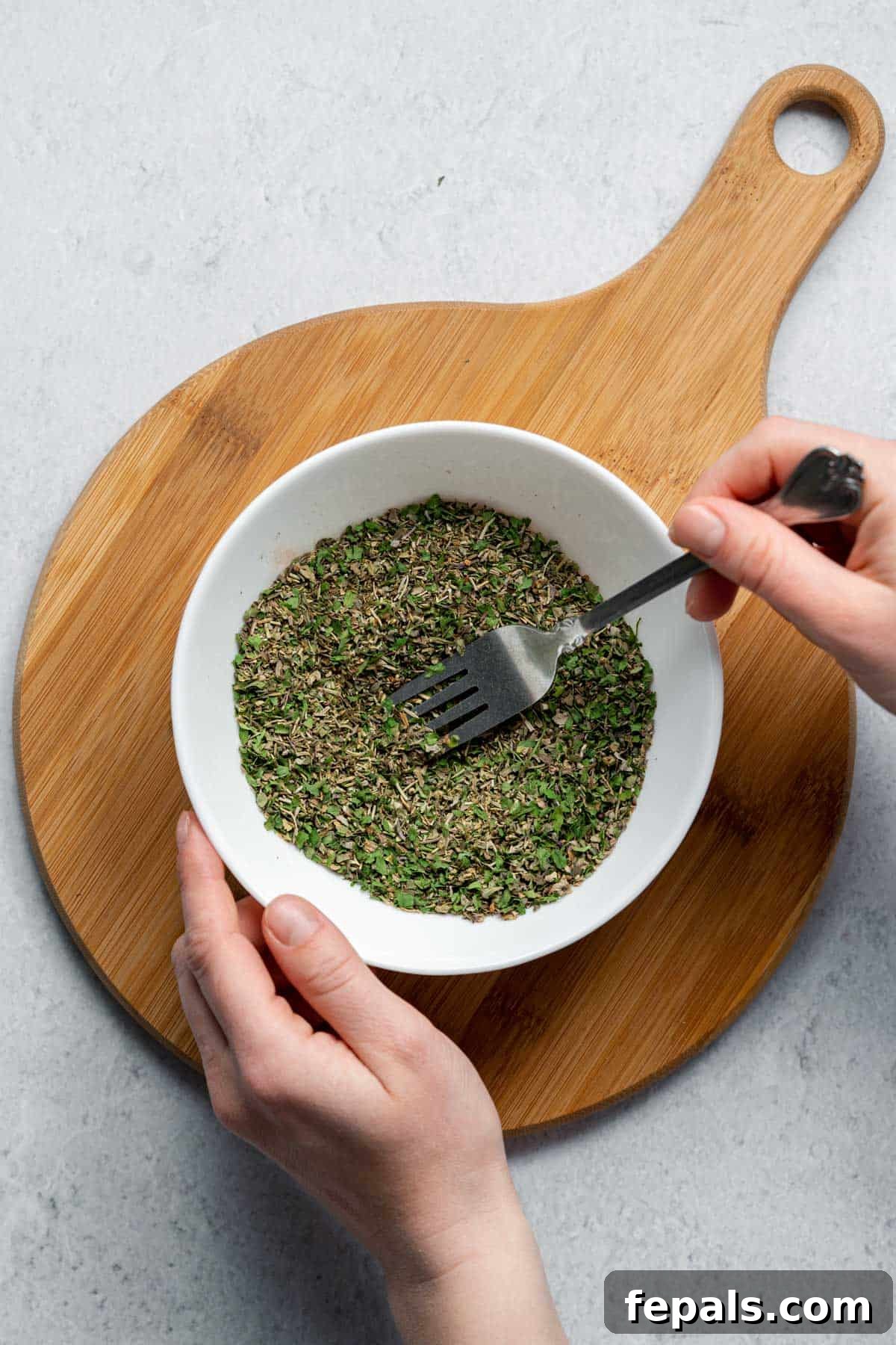 Best Italian Seasoning mixing dried herbs with fork in bowl