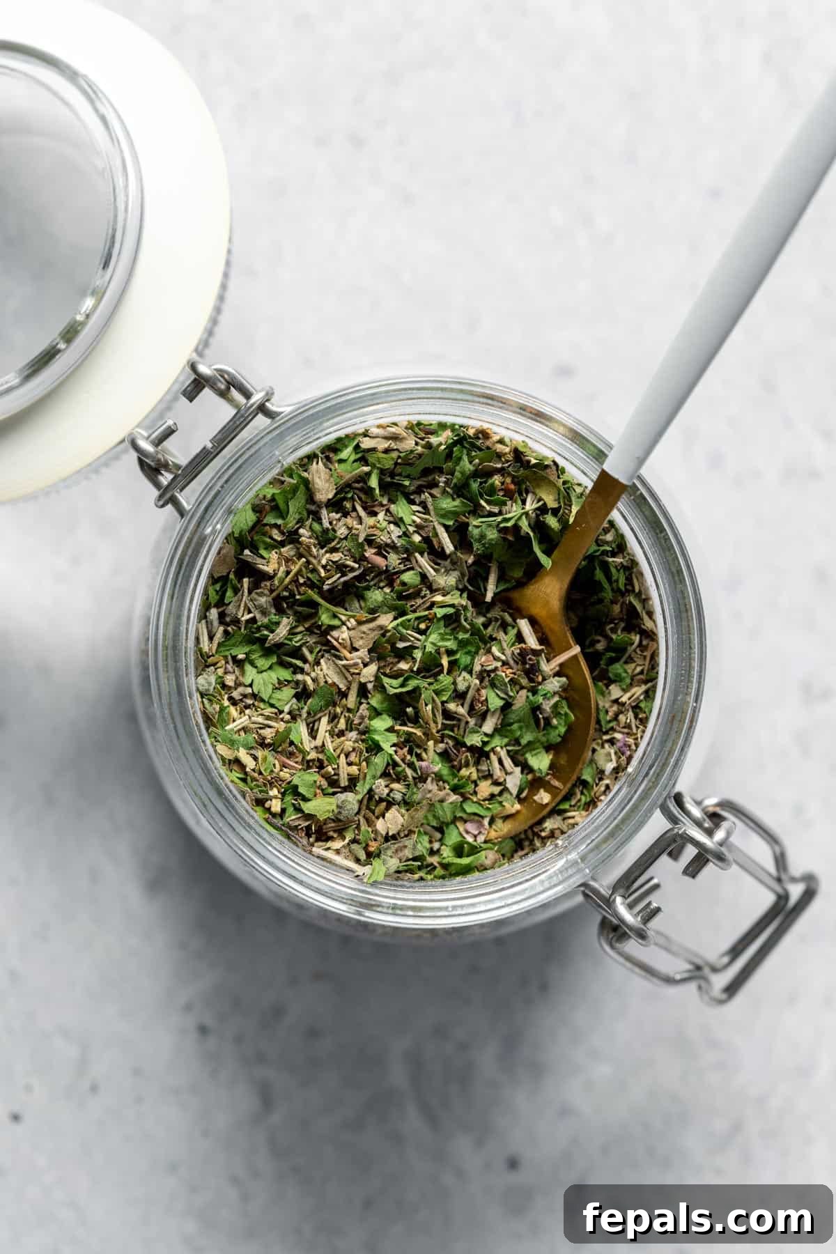Homemade Italian Seasoning jar filled with dried herbs and spoon