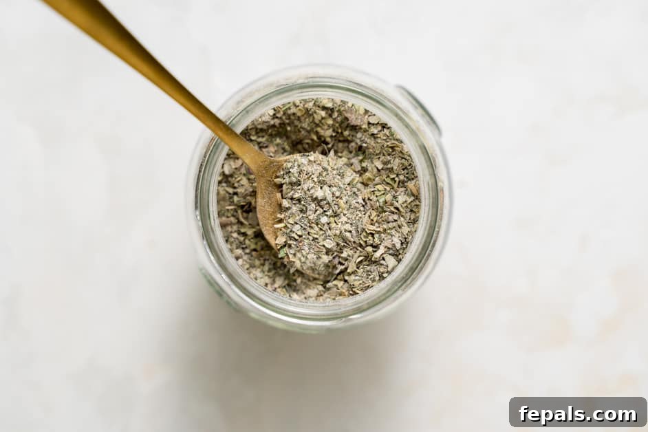 Top view of Greek spice blend in a jar with a spoon, highlighting its texture and color