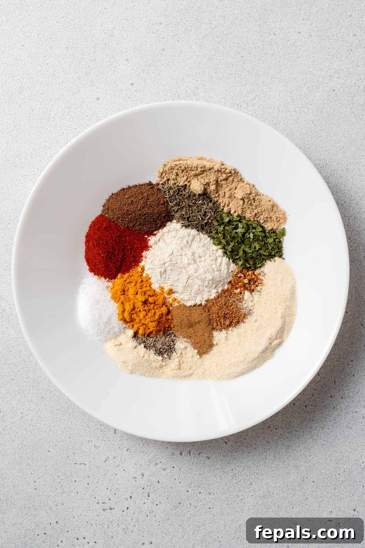 Homemade Jerk Seasoning Close-up of various spices measured out in a bowl, ready for mixing to make homemade jerk seasoning.