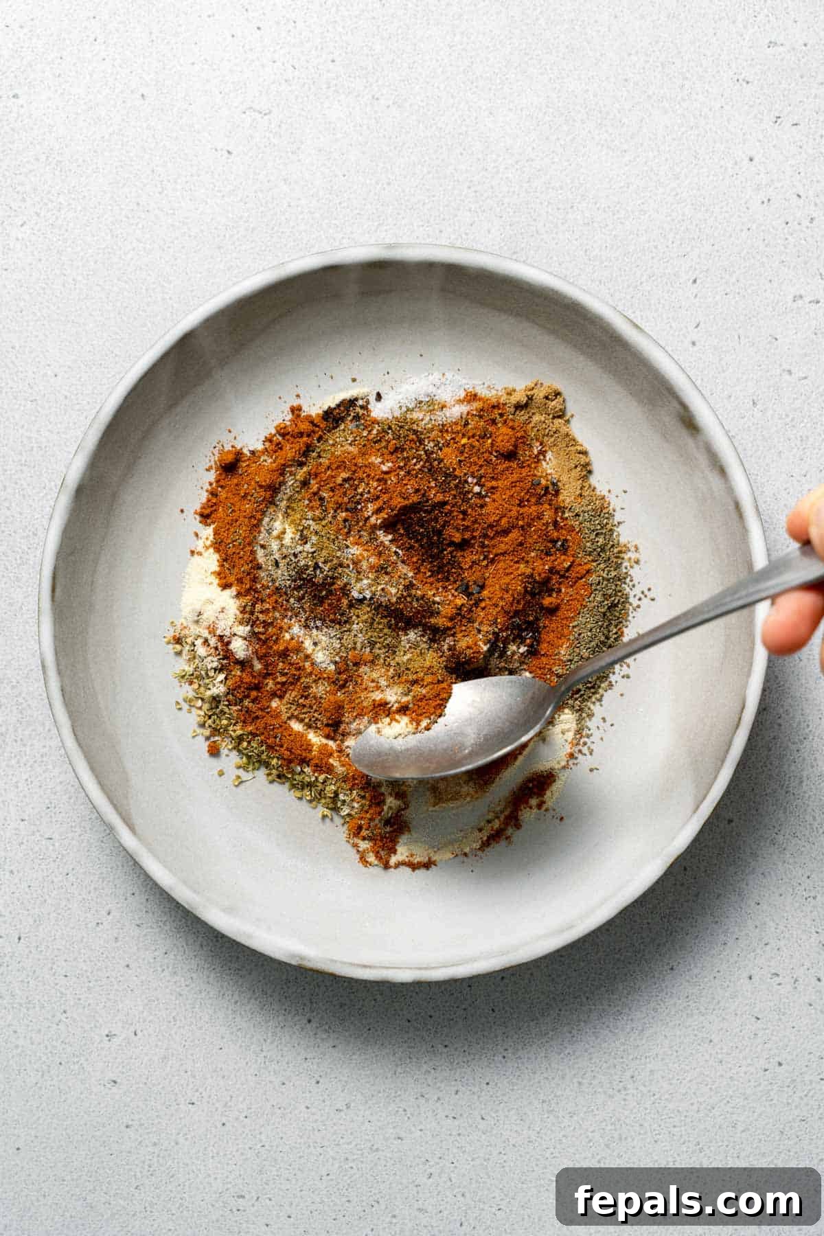 mixing the Mexican spices in a bowl with a spoon