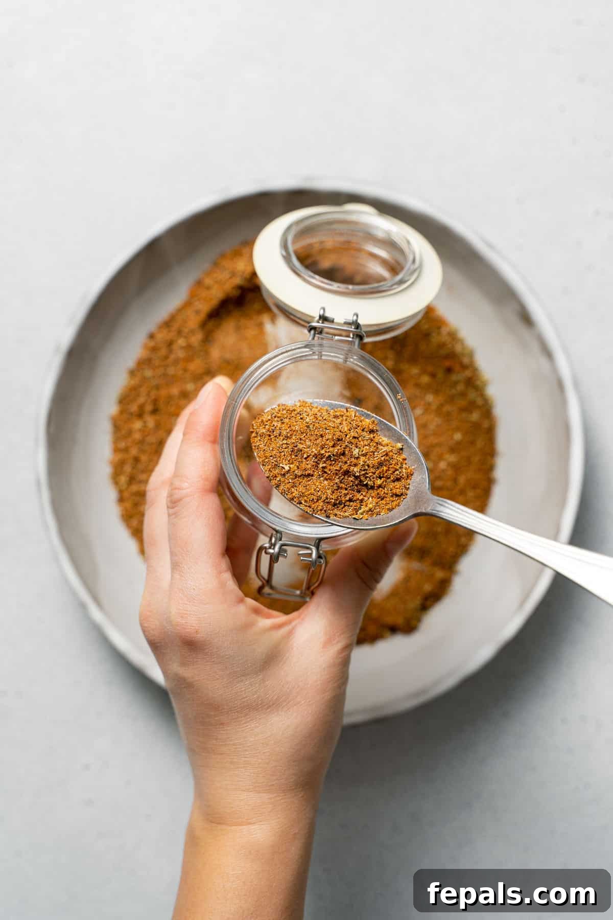 spooning the Mexican spice blend in jar 