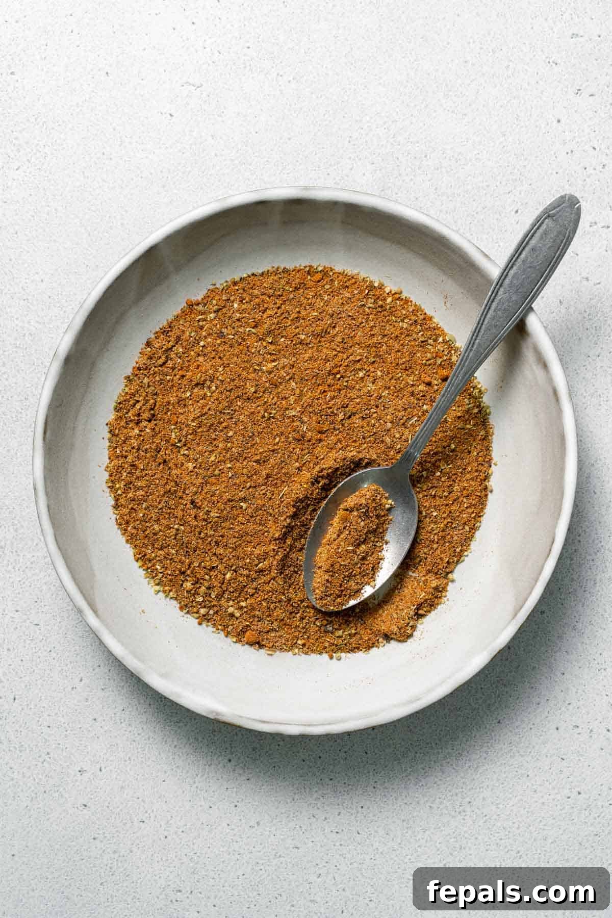 one bowl filled with Mexican seasoning and spoon 