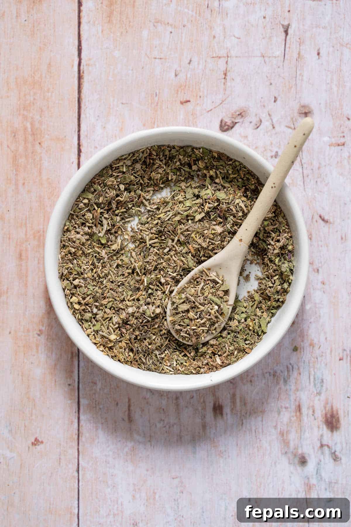 Homemade Poultry Seasoning mixed dried herbs with spoon in bowl