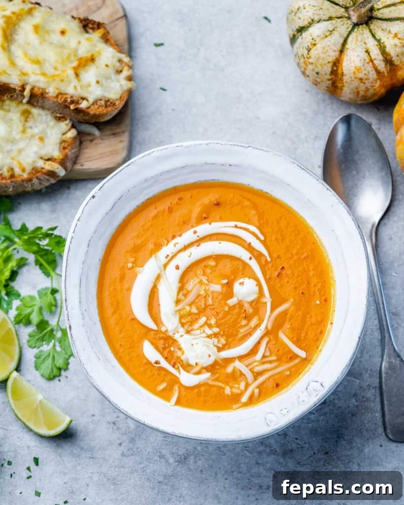 A spoon resting elegantly next to a white bowl filled with creamy butternut squash soup, highlighting its smooth texture and inviting color.