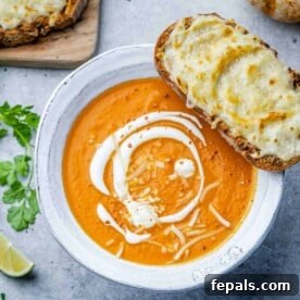 Butternut squash soup in a white bowl with grilled cheesy bread over a bowl.