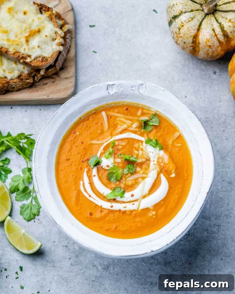Top view of a beautifully presented bowl of butternut squash soup, garnished with a dollop of sour cream and fresh herbs, ready to be enjoyed.
