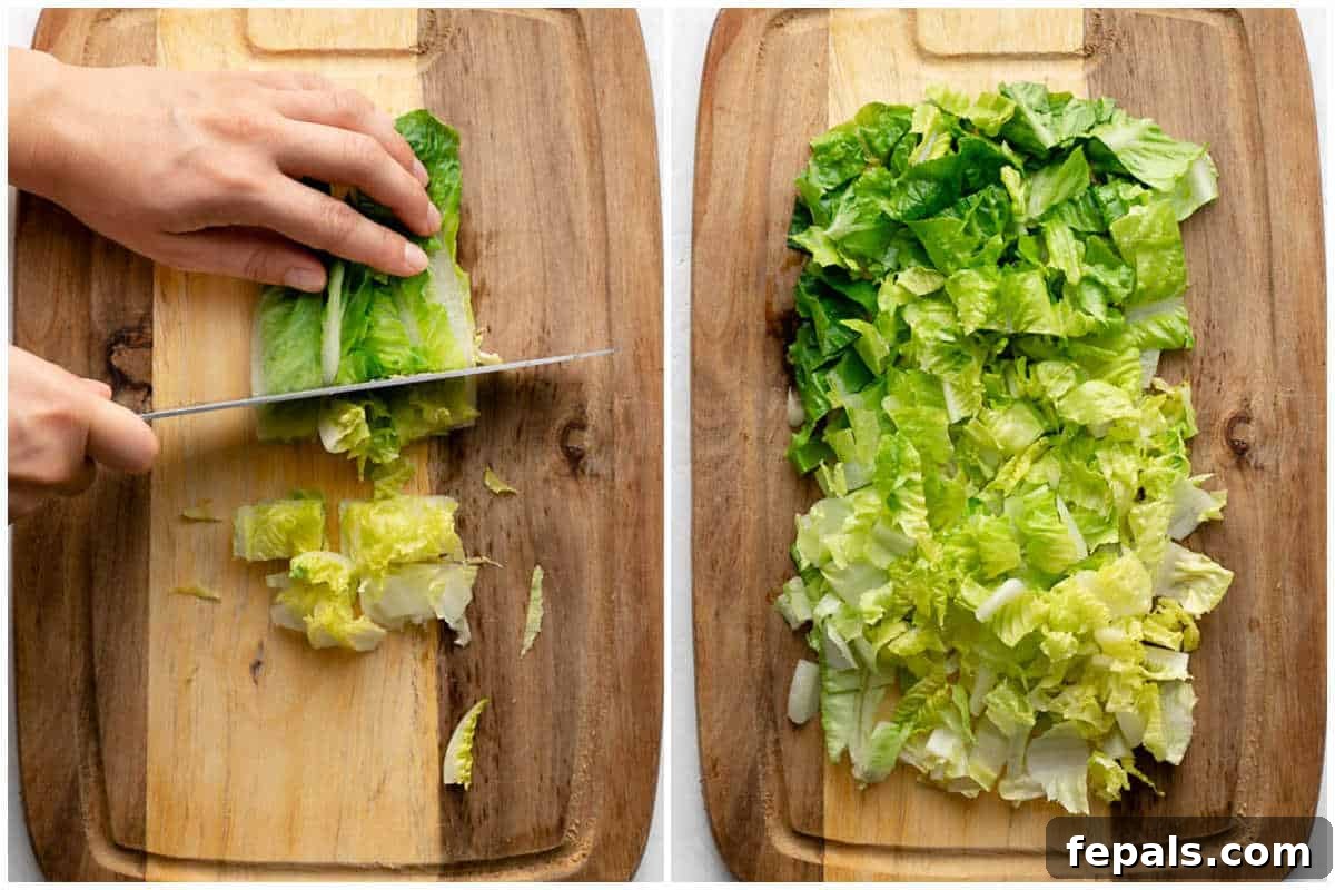 Process shot showing horizontal slicing of vertically cut romaine lettuce to create small, bite-sized pieces on a cutting board.