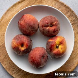 Top view of a plate with five peaches, illustrating the freshness and appeal of the fruit before cutting.