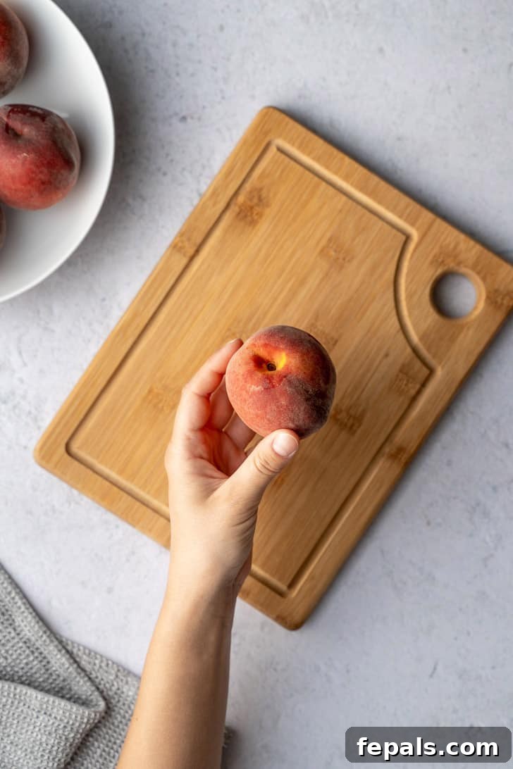 A hand gently holds a ripe peach, ready for the initial cut, illustrating the proper grip for safety and control.
