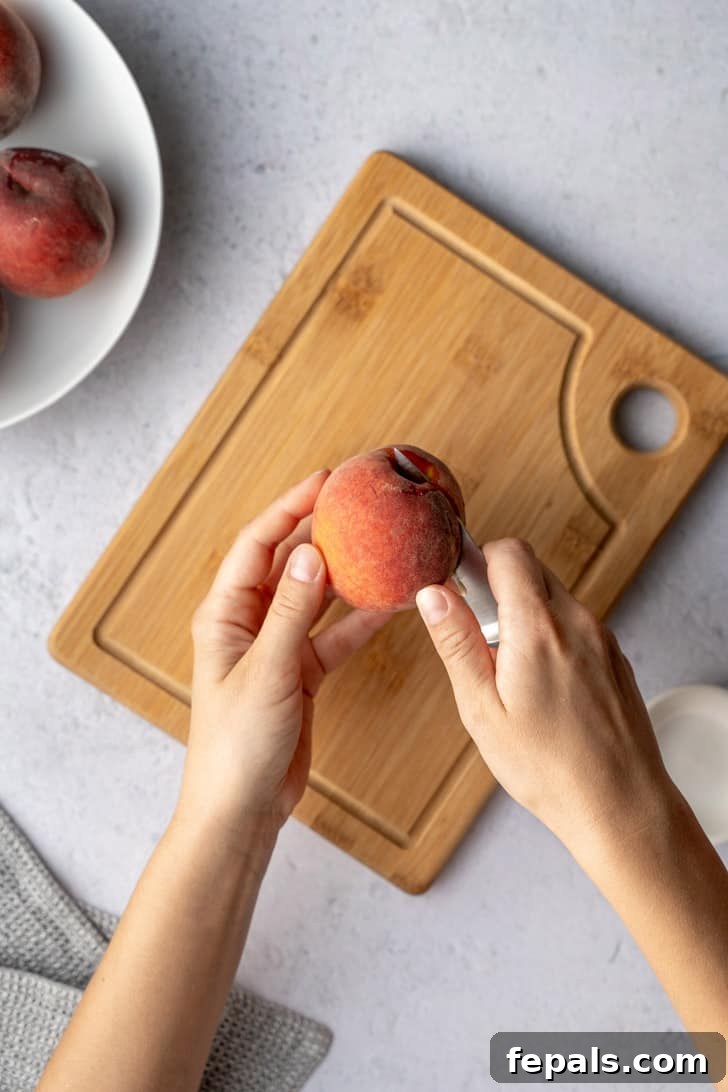 A knife is meticulously slicing through a peach, demonstrating the technique of cutting around the pit to separate the fruit halves.
