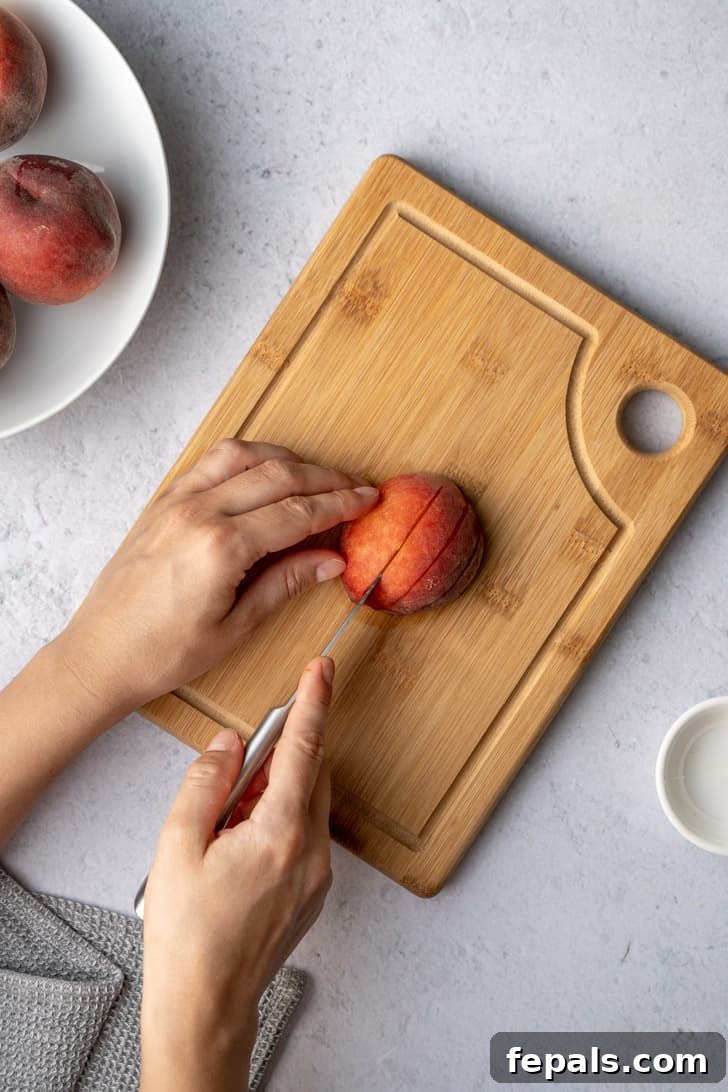 A peach half is expertly sliced on a cutting board, creating uniform pieces perfect for a variety of dishes.