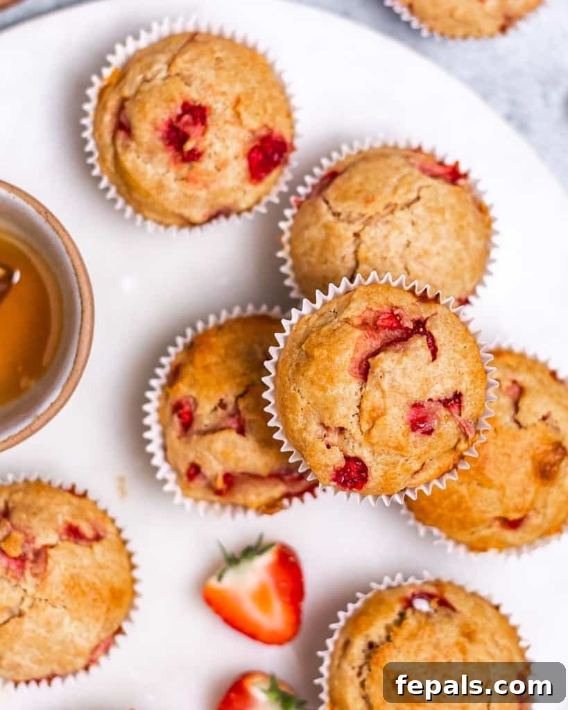 Wholesome Strawberry Muffins 2 Strawberry muffins on a white plate, ready to be enjoyed.