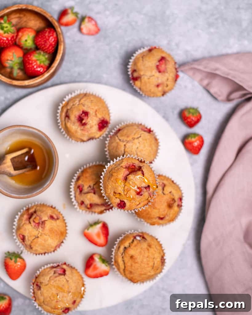 Wholesome Strawberry Muffins 9 Top view of strawberry muffins on a white round surface, ready for serving.