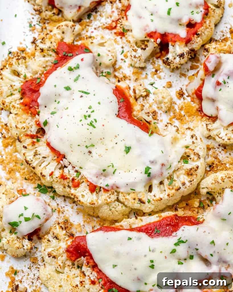 top view of baked cauliflower steaks topped with pizza sauce and melted cheese