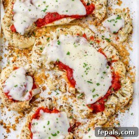 top view of baked cauliflower slices topped with marinara sauce and melted cheese